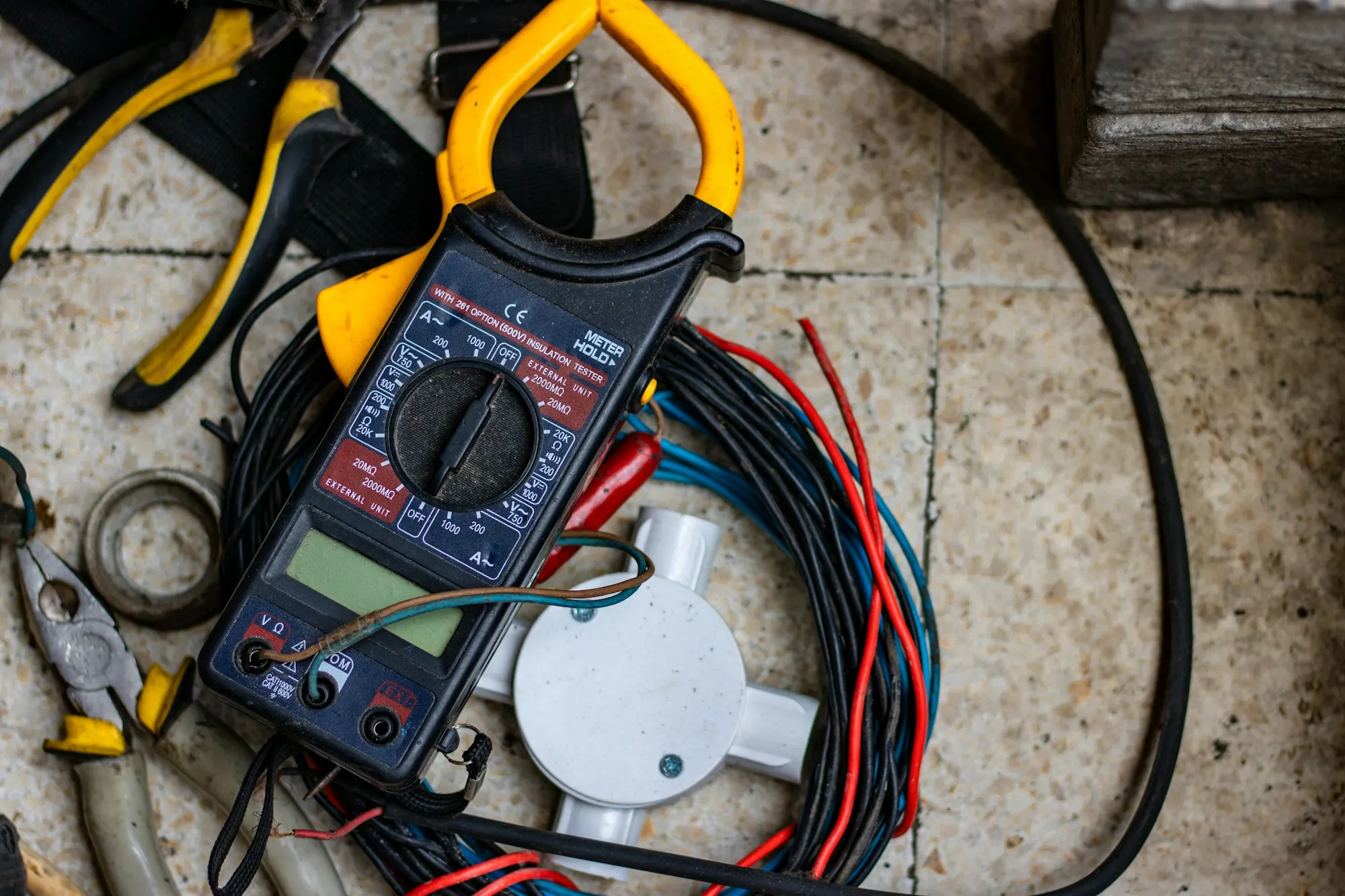 Multimeter and leads resting on electrical cable