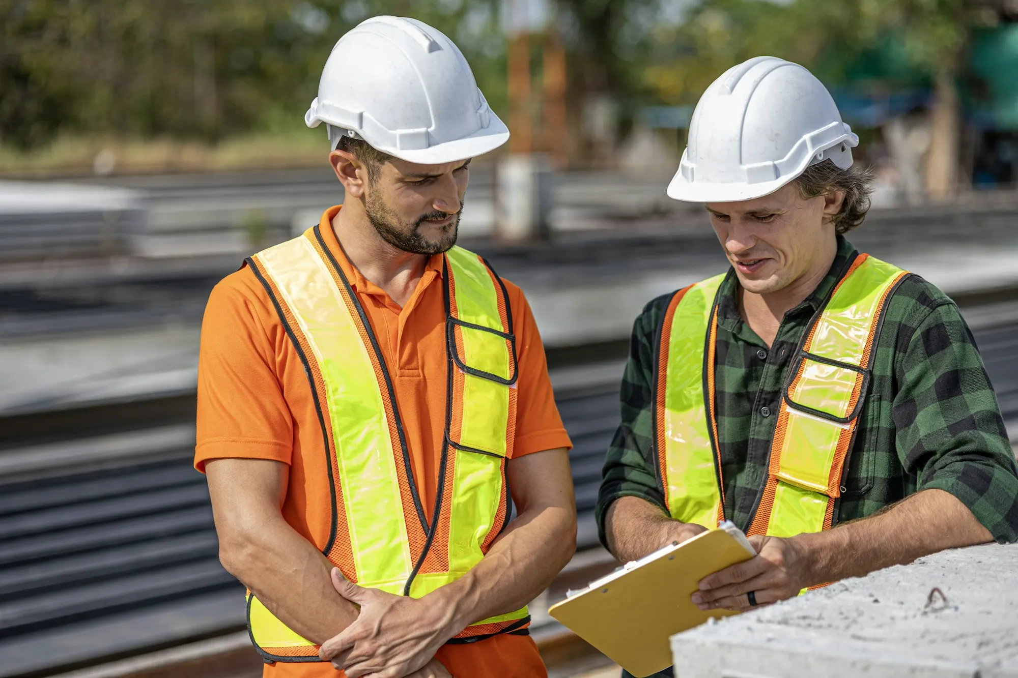 Pair of electricians in hi-vis vests reviewing paperwork outdoors